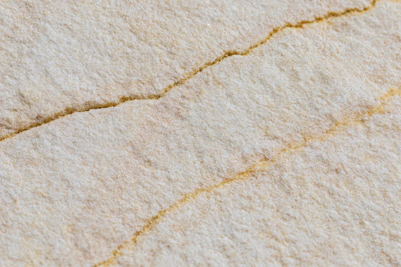 Close-up of a smooth sandstone surface showing natural cracks and layered texture