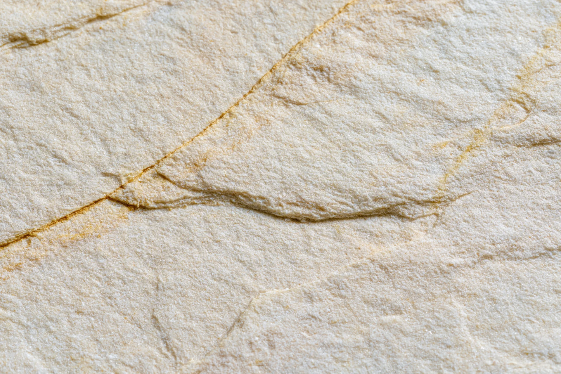 Close-up of a smooth sandstone surface with natural cracks and veins