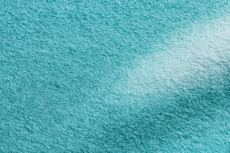 Close-up flat lay of teal-turquoise fabric surface filling the frame