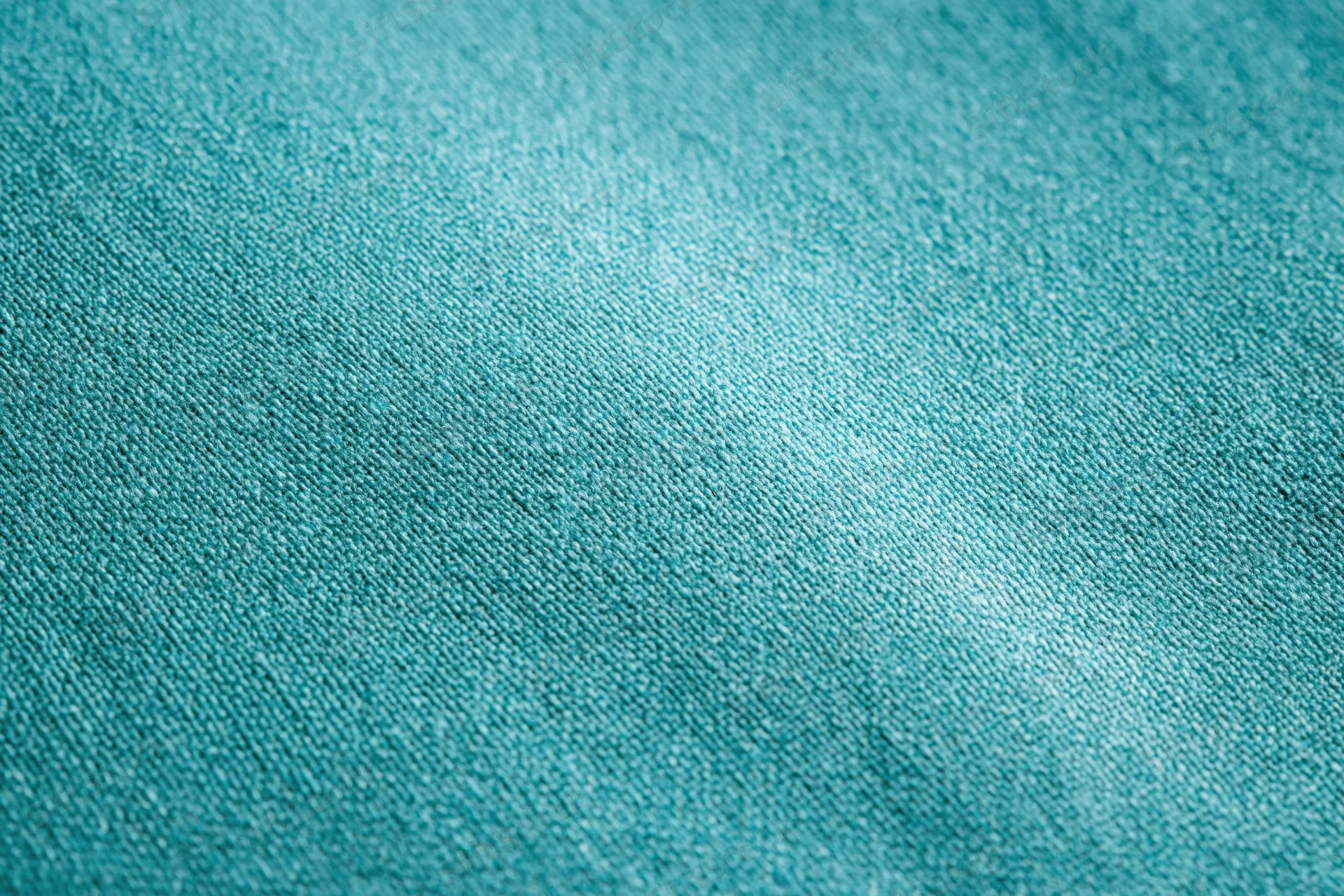 Close-up flat lay of teal-turquoise fabric surface filling the frame