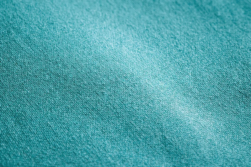 Close-up flat lay of teal-turquoise fabric surface filling the frame