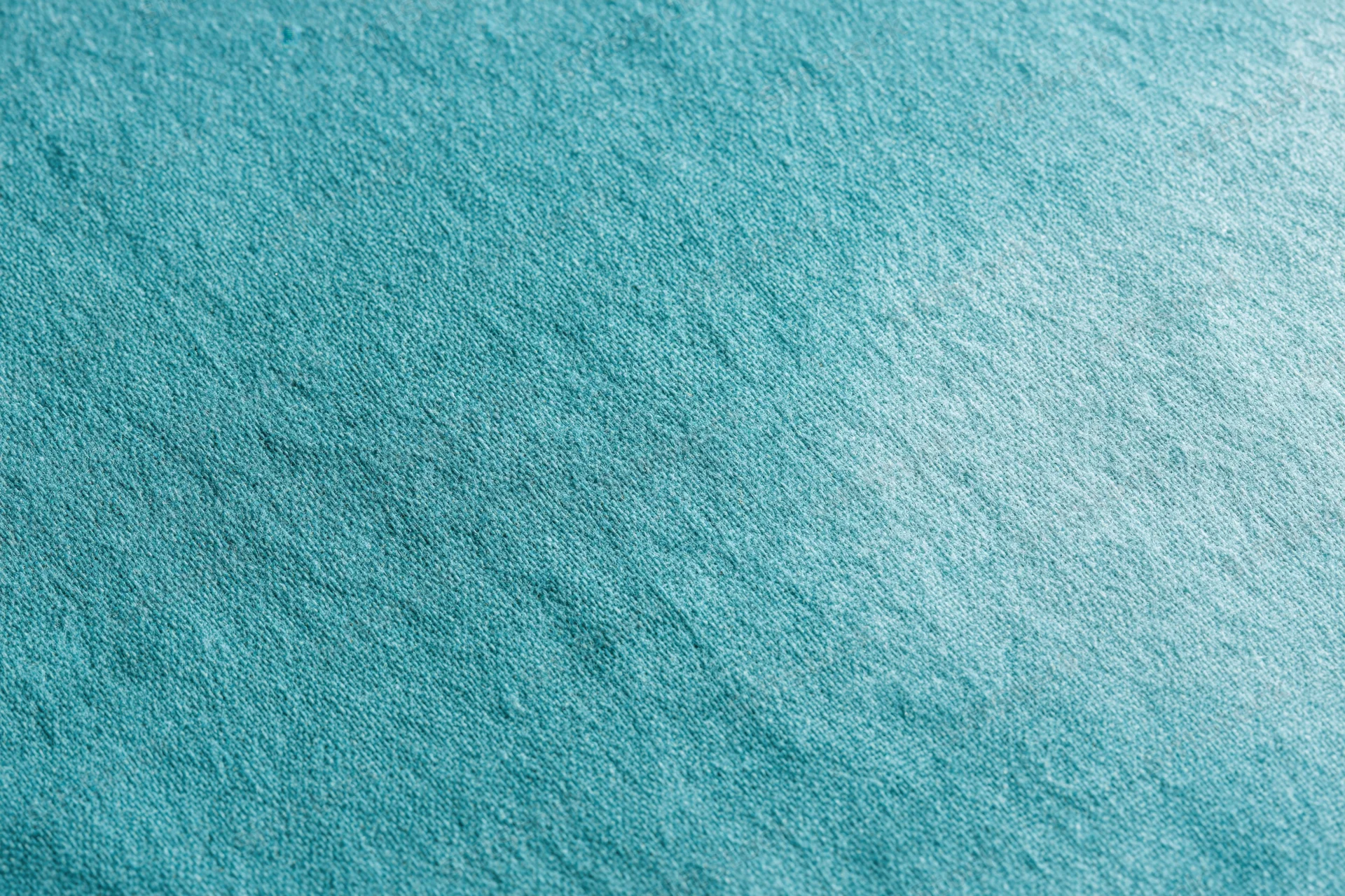 Close-up flat lay of teal-turquoise fabric surface filling the frame