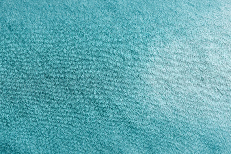 Close-up flat lay of teal-turquoise fabric surface filling the frame