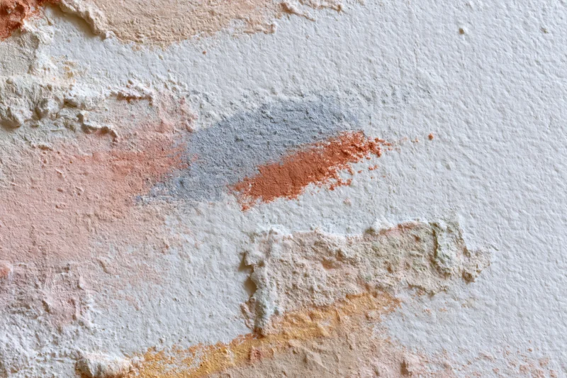 Textured painted canvas surface with layered abstract paint strokes in soft peach, orange, gray and beige tones