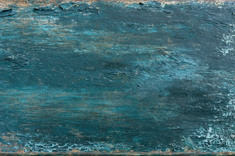 Weathered painted metal surface with peeling blue-green paint and rust, flat lay closeup