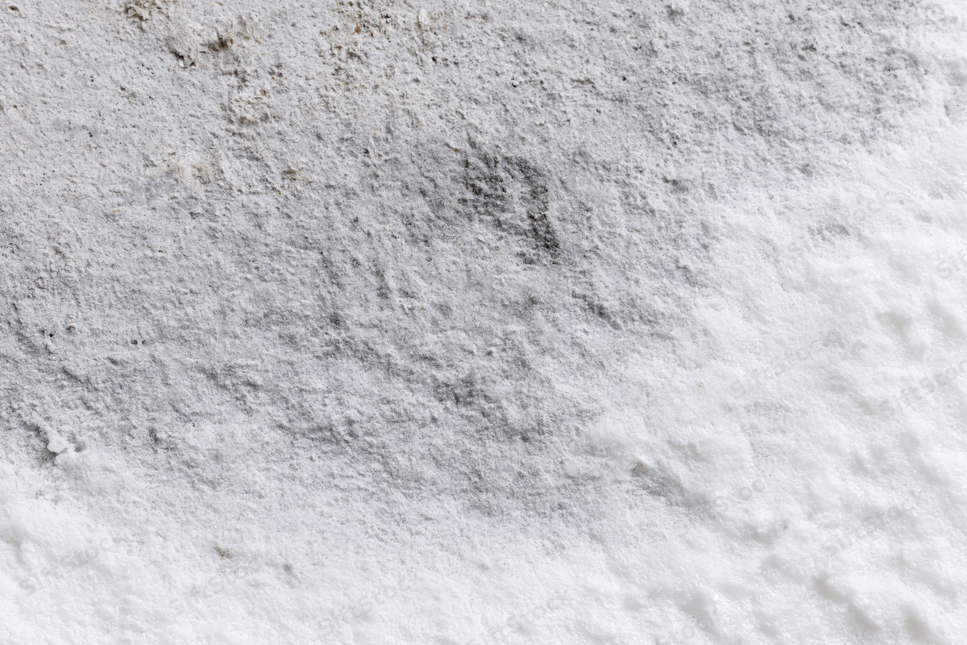 Weathered white concrete surface with rough texture and gray stains