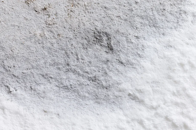 Weathered white concrete surface with rough texture and gray stains