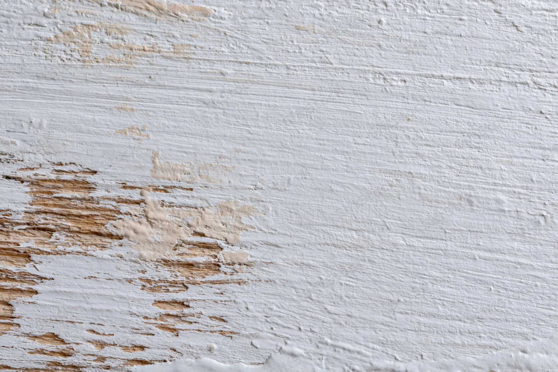 Weathered wooden surface with peeling white paint showing natural wood grain and texture