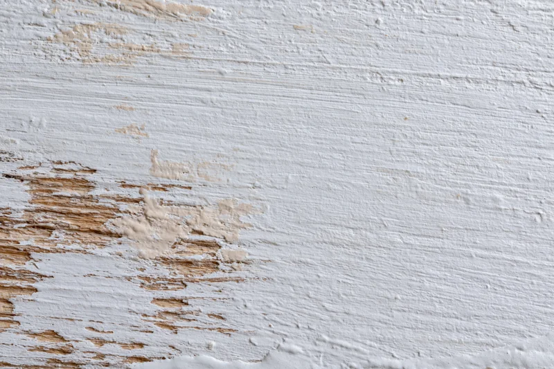 Weathered wooden surface with peeling white paint showing natural wood grain and texture