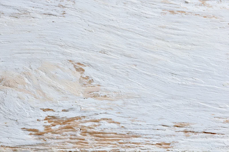 Weathered wooden surface painted white with peeling paint and visible grain
