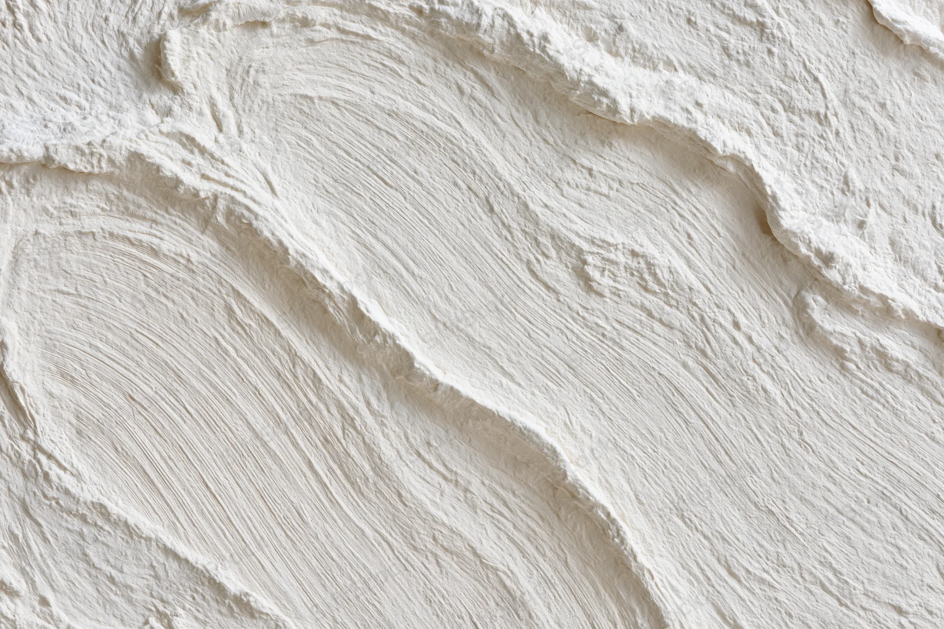 Close-up of white textured wall surface with visible brushstroke patterns and undulating relief