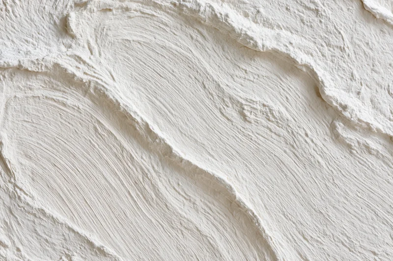 Close-up of white textured wall surface with visible brushstroke patterns and undulating relief