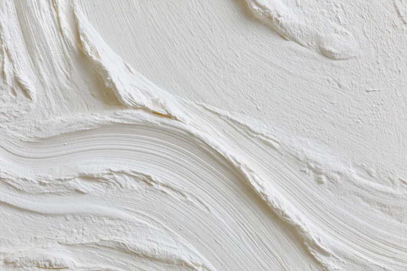 Close-up of white textured wall surface with visible brushstroke sweep