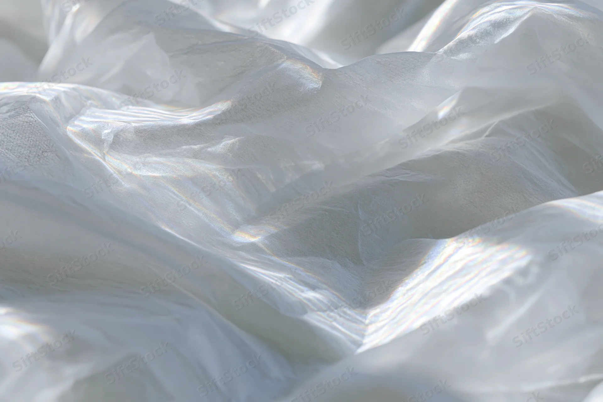 Crumpled white translucent fabric with soft folds and light sheen in close-up view