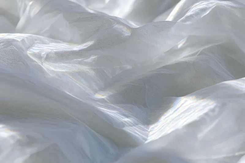 Crumpled white translucent fabric with soft folds and light sheen in close-up view