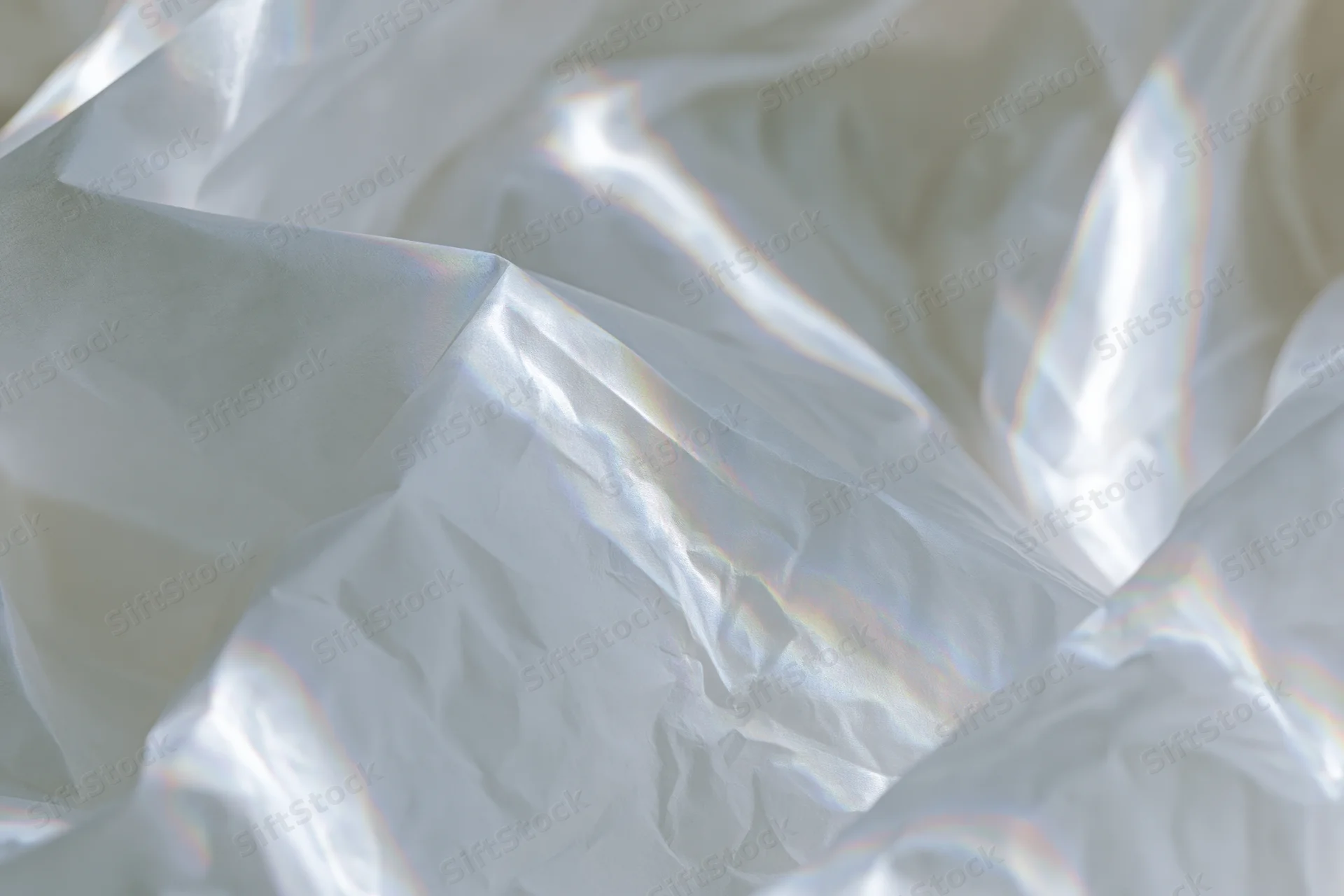 Crumpled white translucent fabric with iridescent sheen in flat lay arrangement
