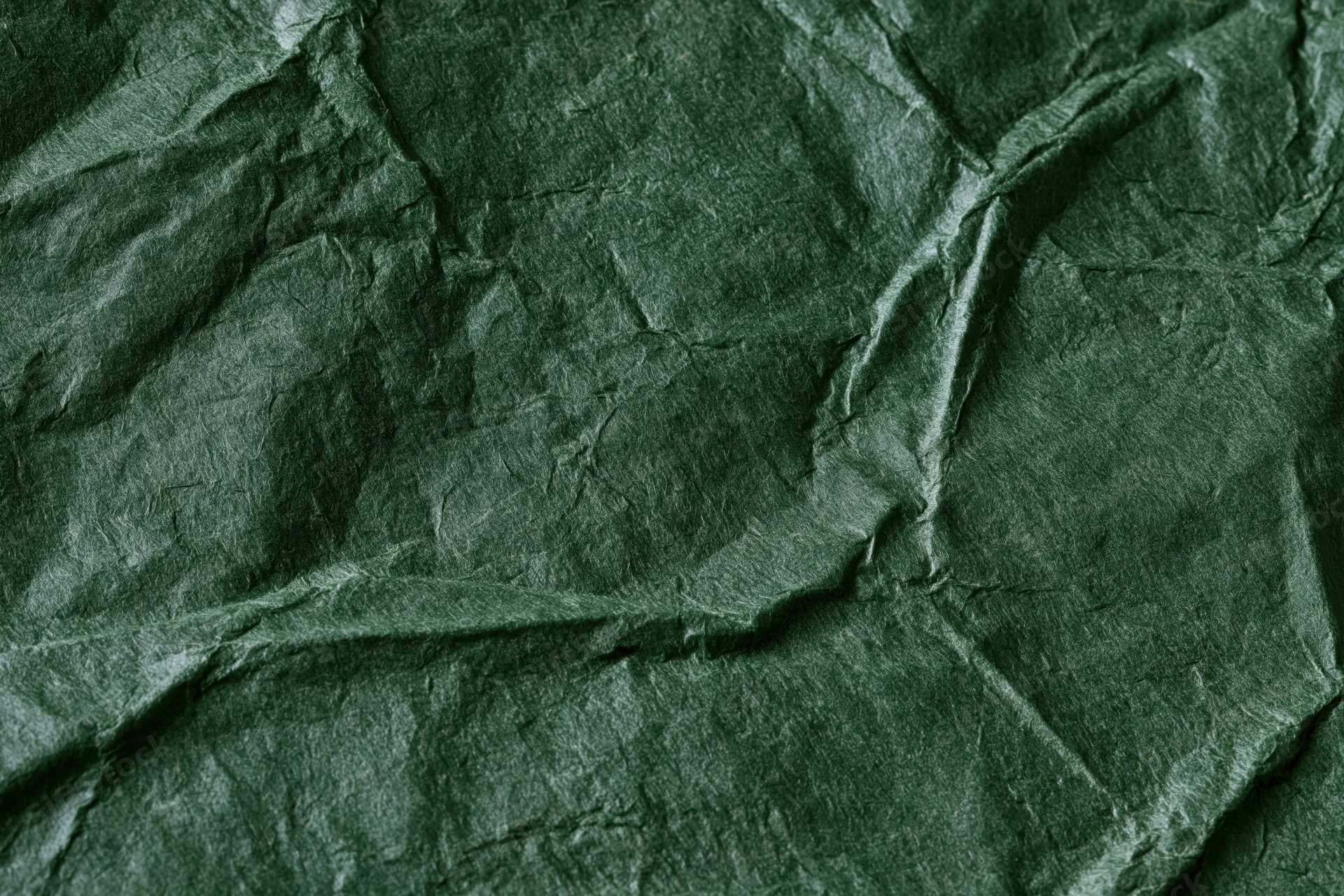 Crumpled dark forest green paper in flat lay closeup showing texture and folds