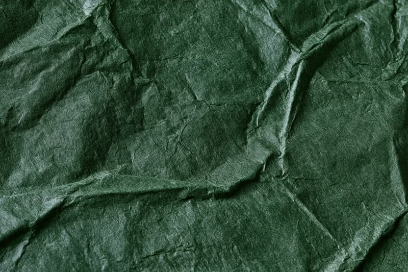 Crumpled dark forest green paper in flat lay closeup showing texture and folds