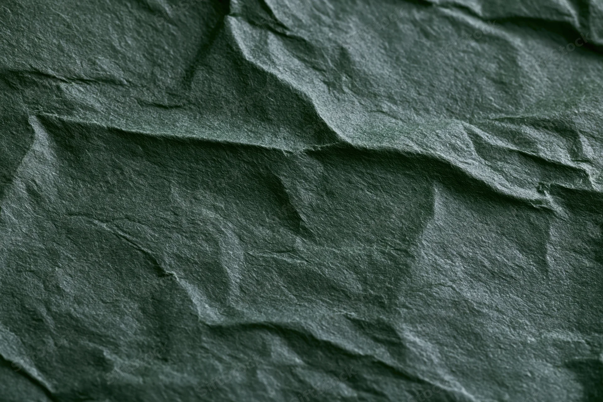 Crumpled dark forest green paper in flat lay closeup showing texture and folds