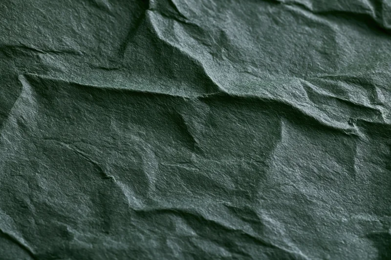 Crumpled dark forest green paper in flat lay closeup showing texture and folds