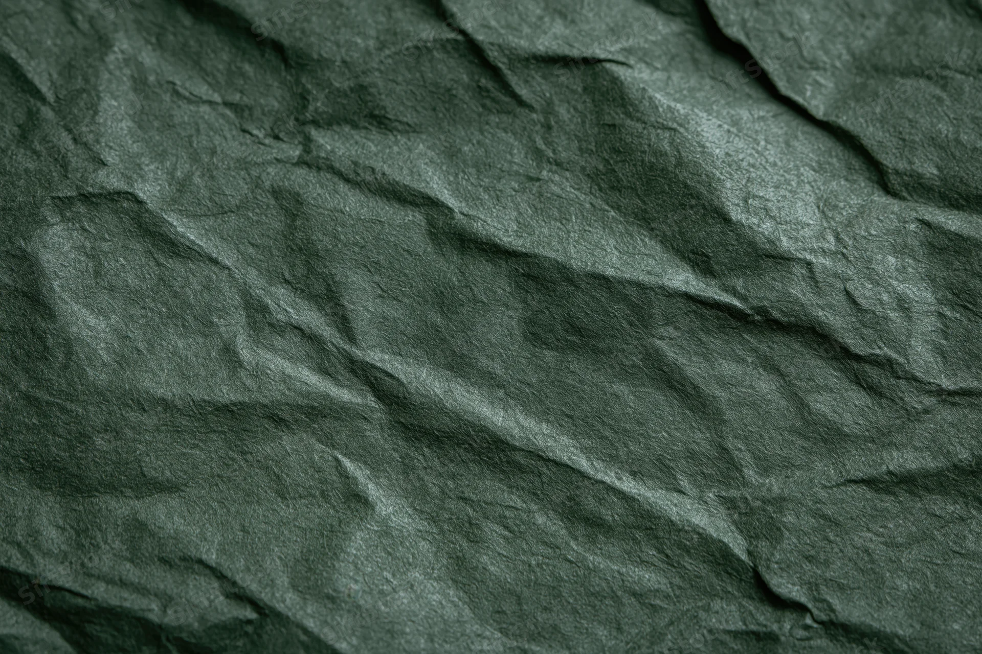 Crumpled dark forest green paper in flat lay closeup showing texture and folds