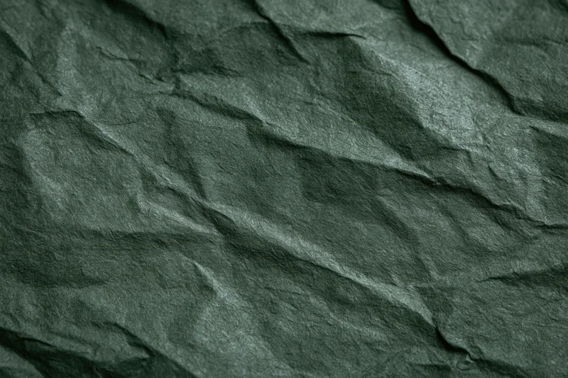 Crumpled dark forest green paper in flat lay closeup showing texture and folds