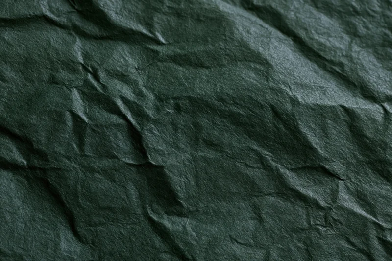 Crumpled dark forest green paper in flat lay arrangement showing texture and creases