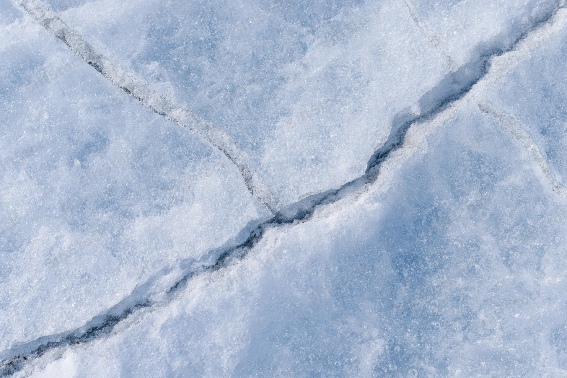 Frozen lake ice surface with diagonal cracks in winter landscape