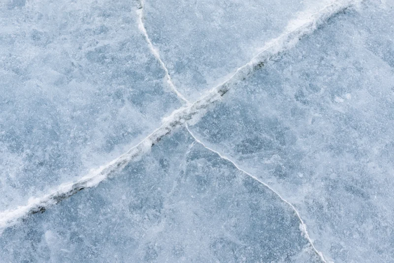 Close-up flat lay of frozen lake ice surface with long diagonal cracks