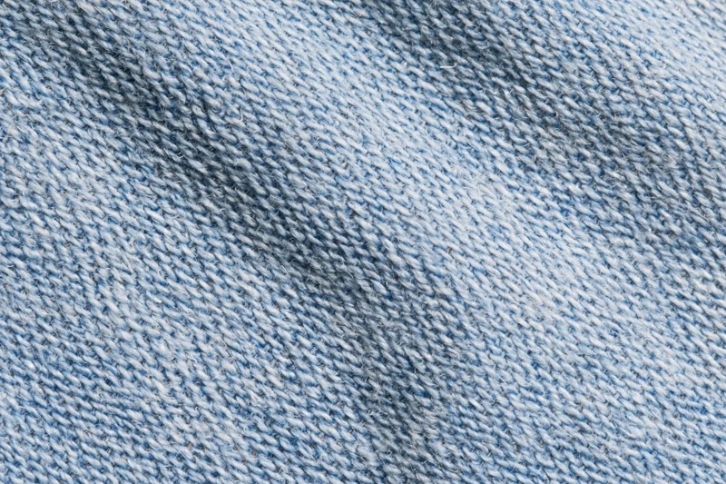 Close-up flat lay of light-wash denim fabric filling the frame