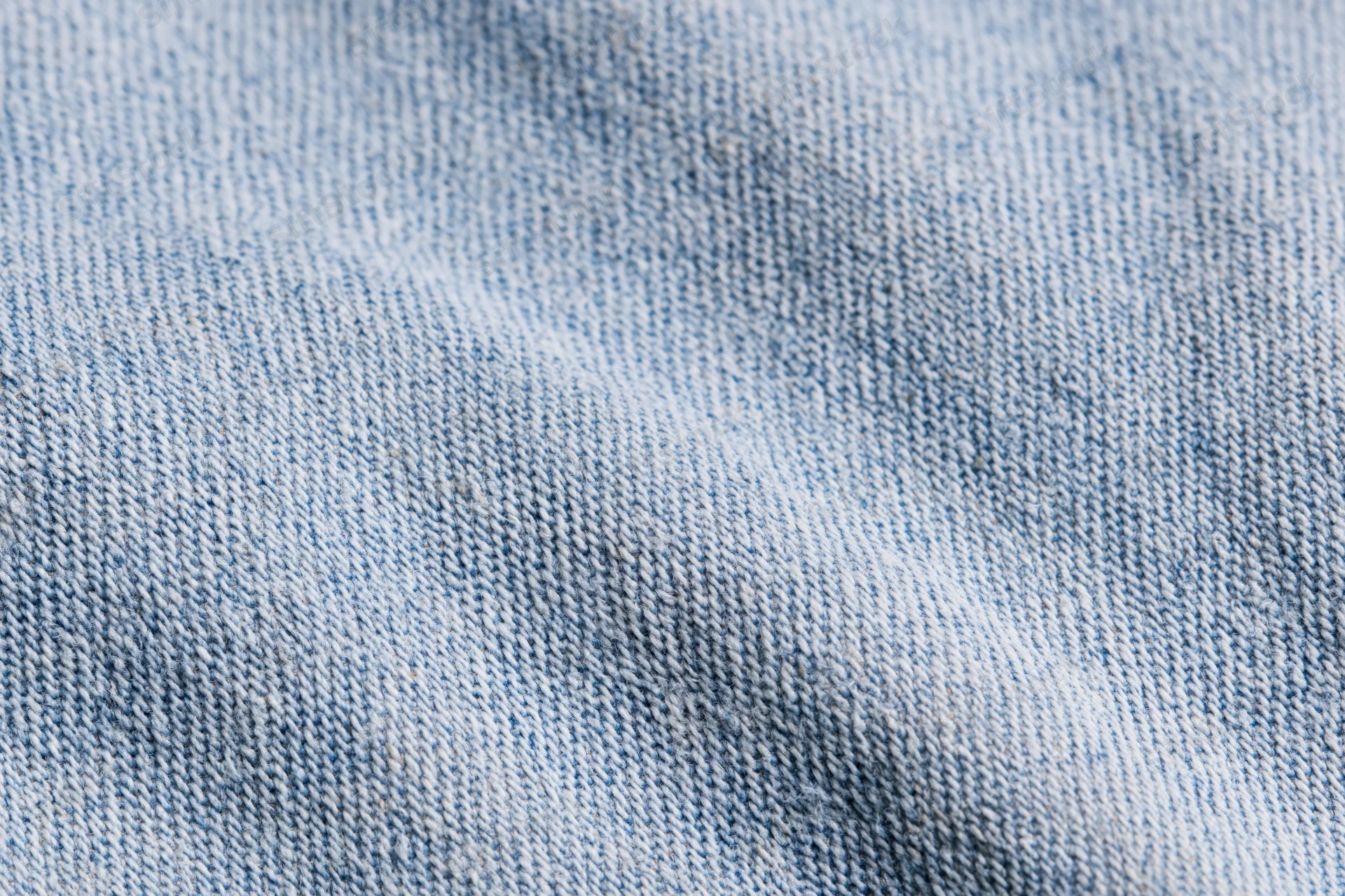 Close-up flat lay of light-wash denim fabric filling the frame