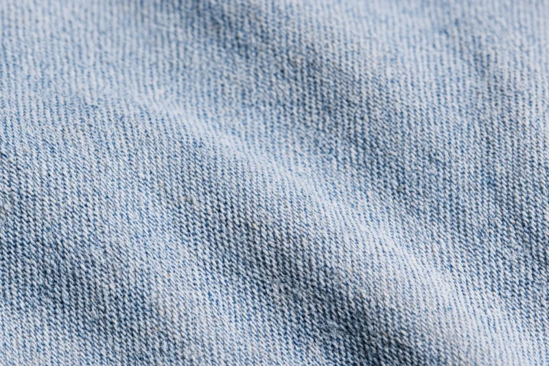 Close-up flat lay of light-wash denim fabric filling the frame