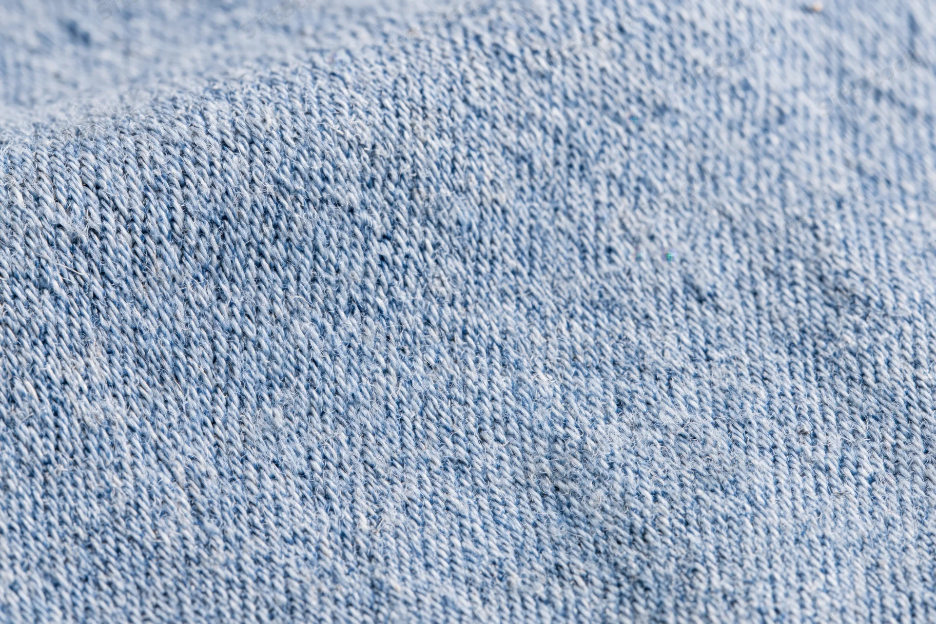 Close-up of light-wash denim fabric in flat lay arrangement filling the frame