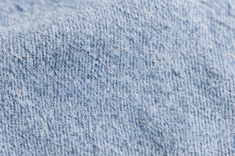 Close-up of light-wash denim fabric in flat lay arrangement filling the frame