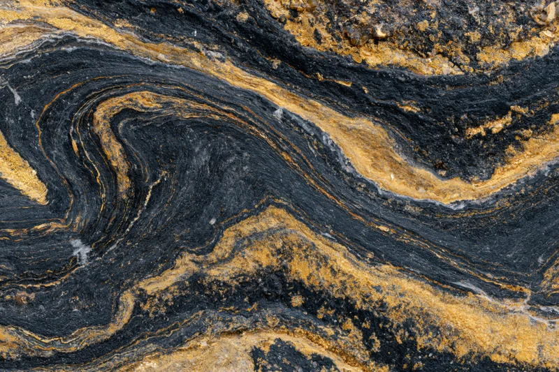 Polished black marble surface with swirling gold veining, flat lay close-up
