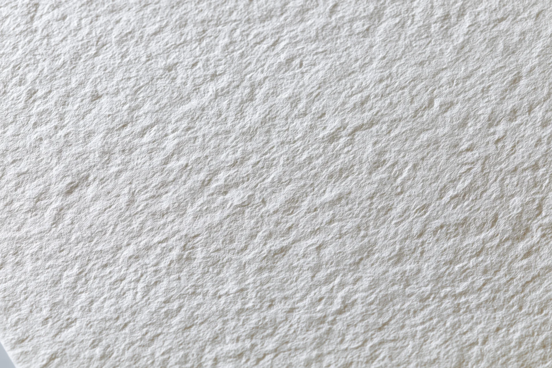 Textured white watercolor paper filling the frame in a flat lay closeup