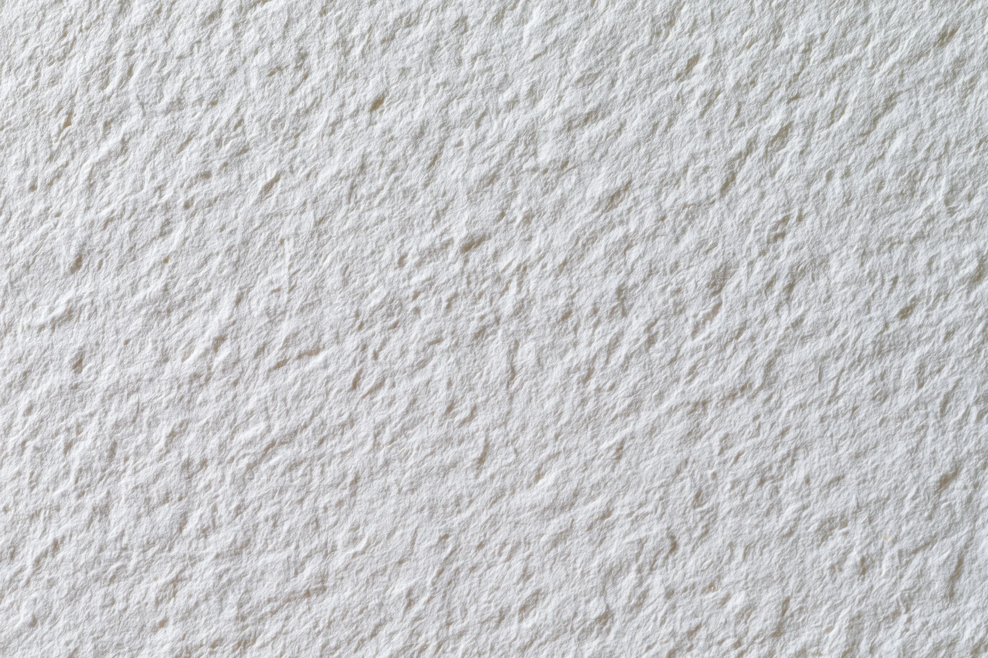 Textured white watercolor paper filling the frame in a flat lay closeup