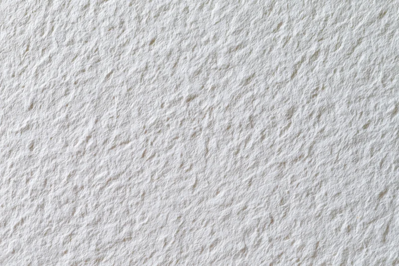 Textured white watercolor paper filling the frame in a flat lay closeup