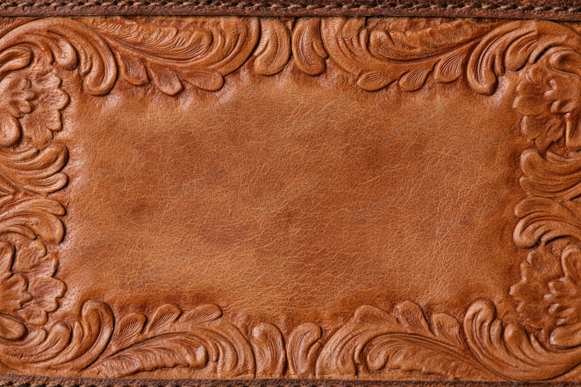 Tooled leather surface with embossed floral border in flat lay arrangement
