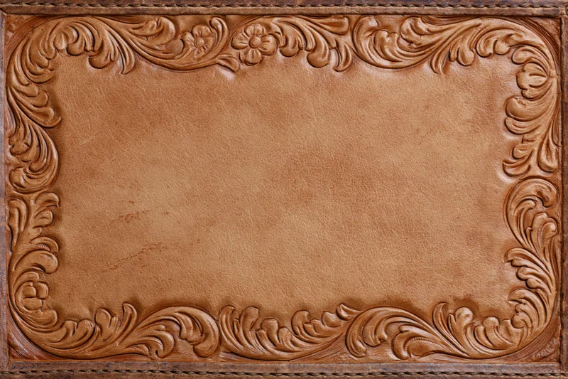 Tooled leather surface with embossed floral border and central copyspace