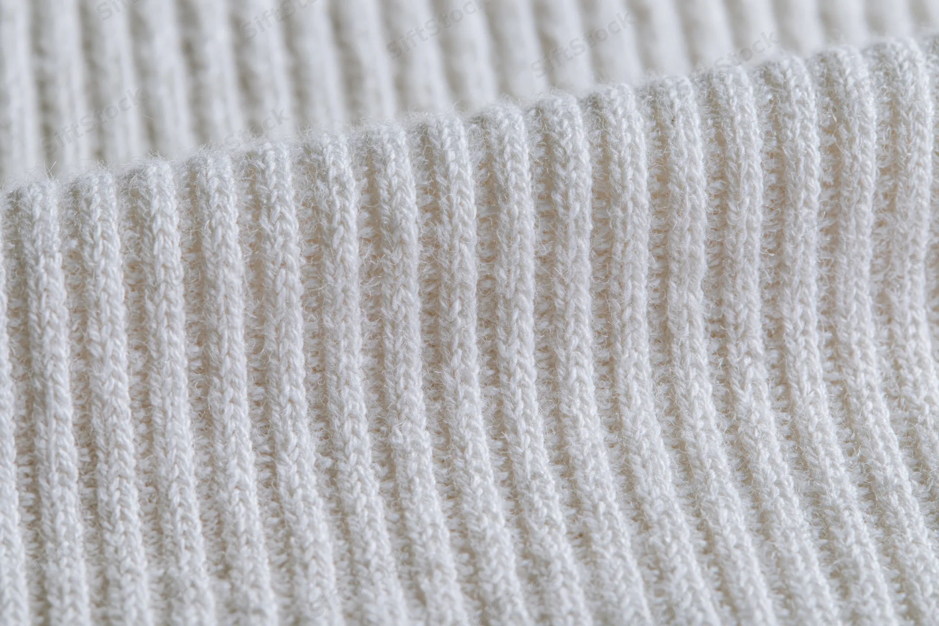Close-up of white ribbed cotton knit fabric laid flat filling the frame