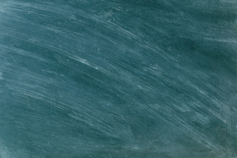 Close-up of a blank chalkboard surface with chalk residue and diagonal smudges in a classroom setting