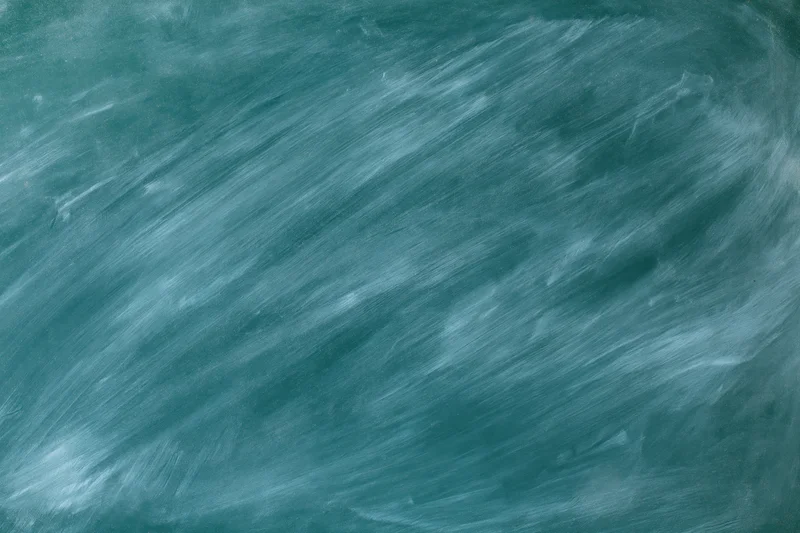 Close-up of a blank chalkboard surface with smudged white residue and green background in a classroom setting