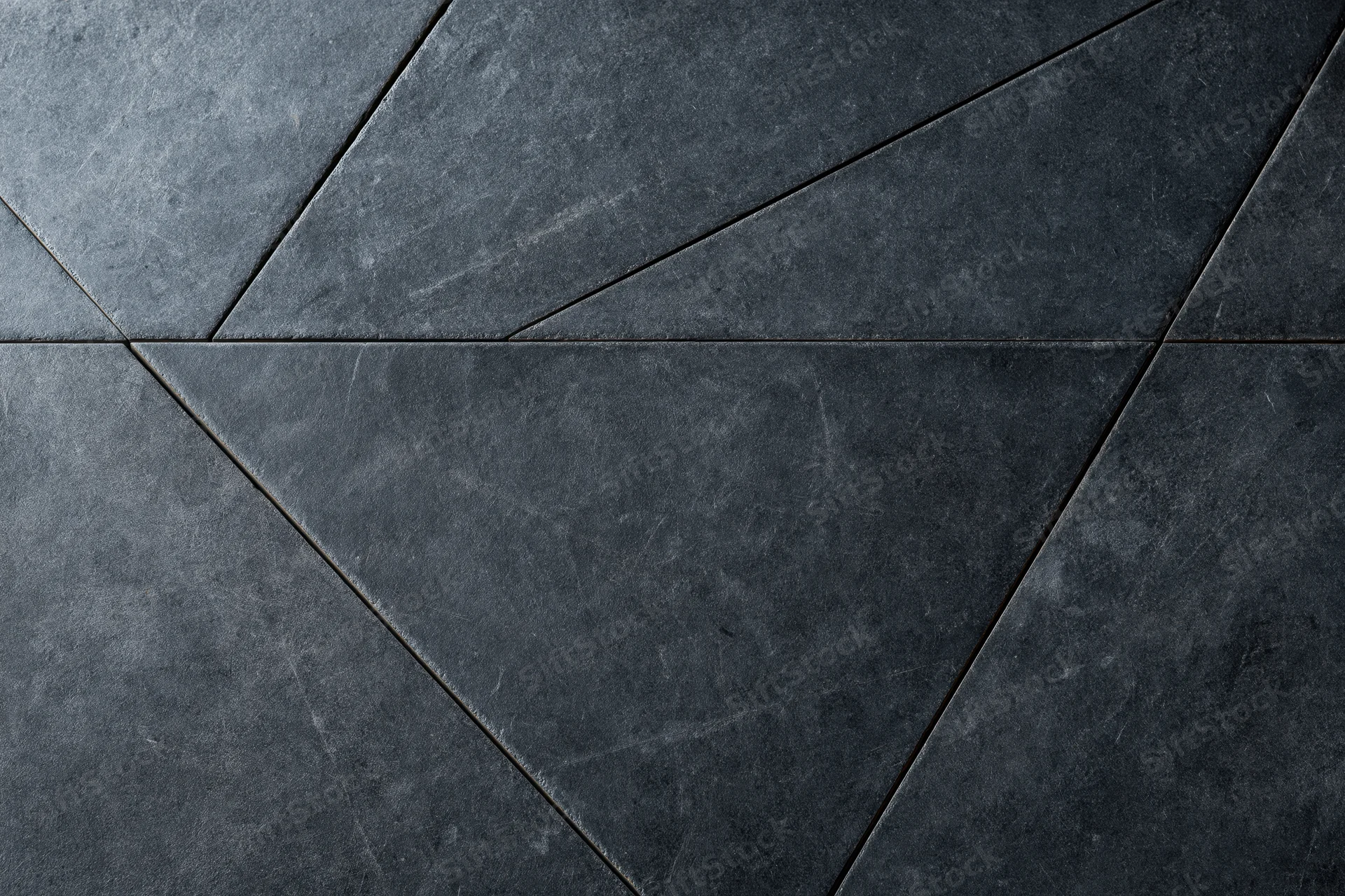 Dark slate and concrete wall surface with geometric triangular pattern and rough texture
