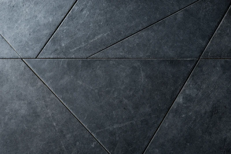 Dark slate and concrete wall surface with geometric triangular pattern and rough texture