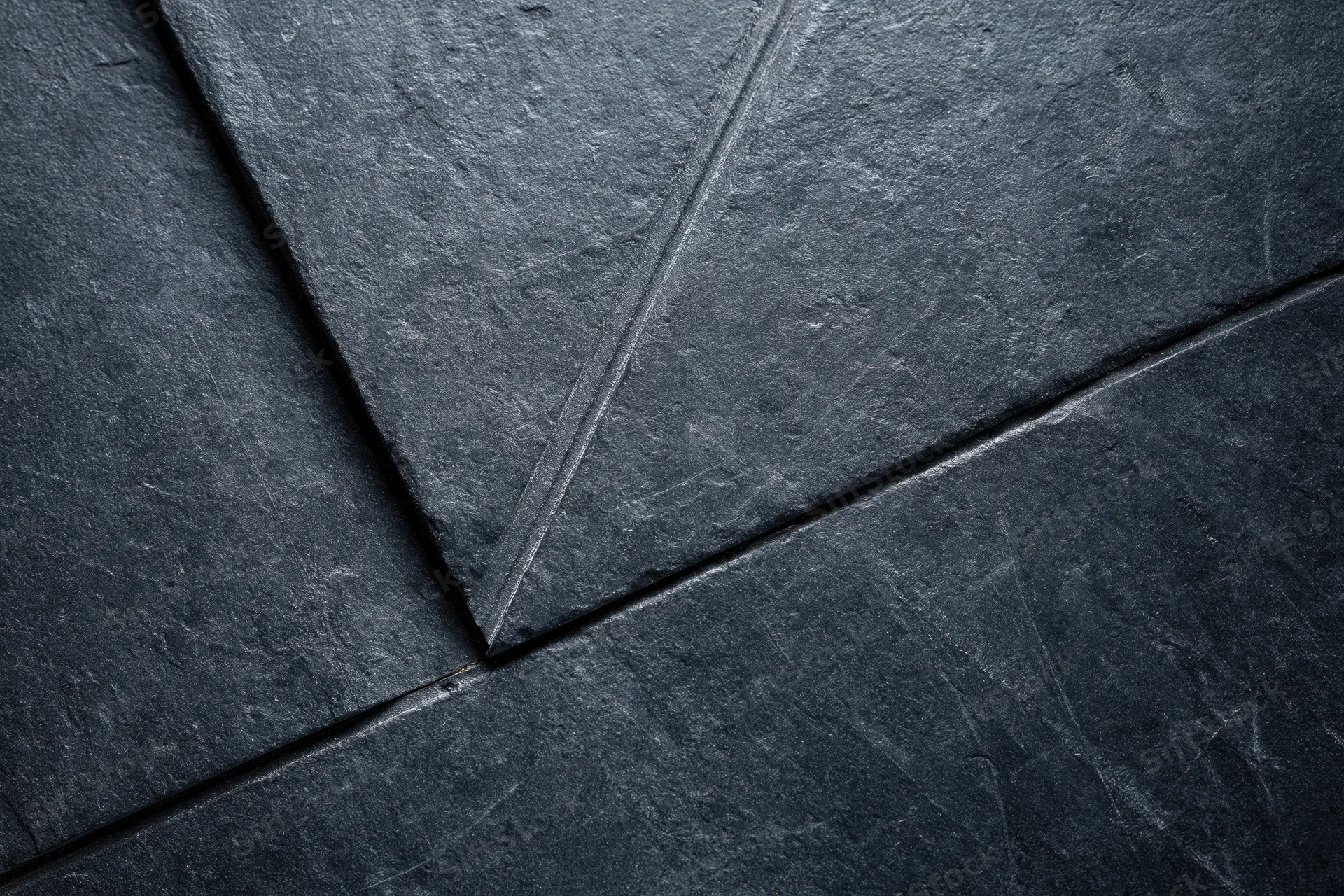 Dark slate wall surface with diagonal stone tiles and visible seams