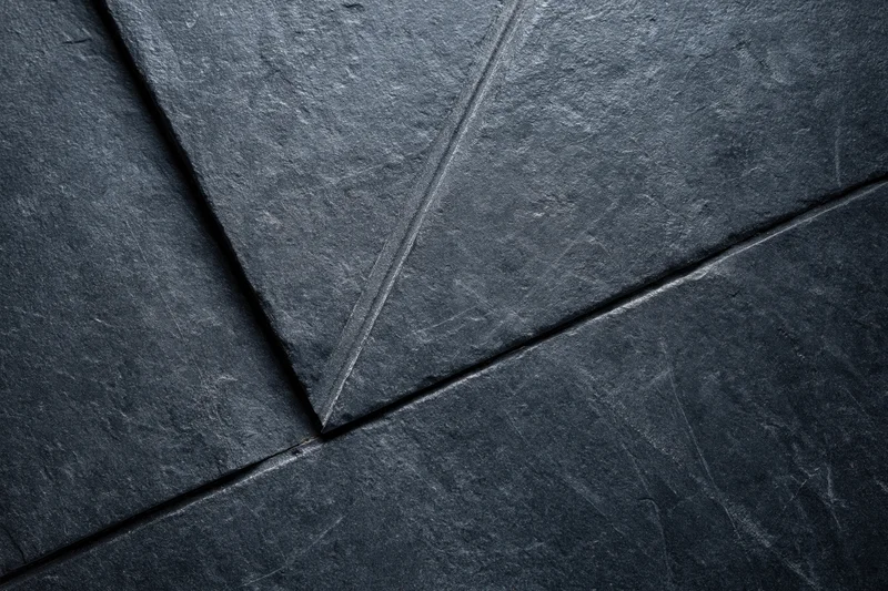 Dark slate wall surface with diagonal stone tiles and visible seams