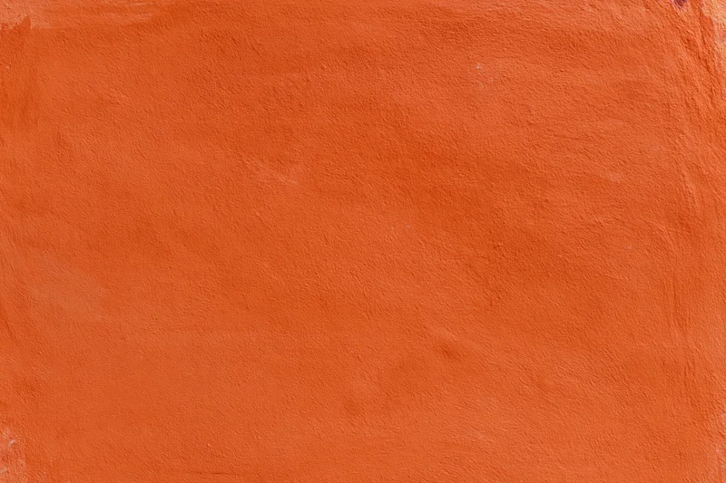 Close-up of an orange stucco plaster wall with textured surface and copyspace