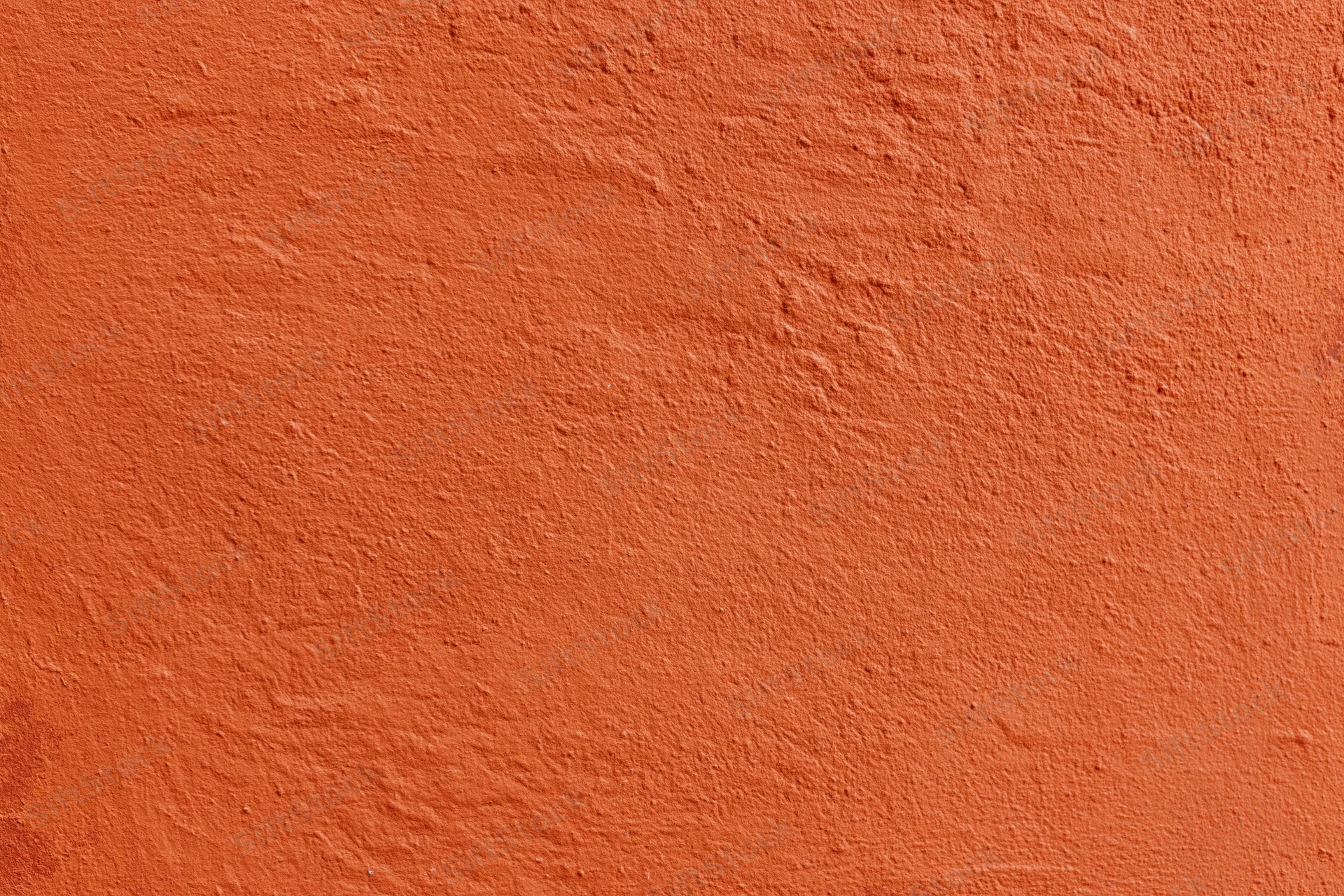 Close-up of an orange stucco plaster wall with rough texture and even lighting