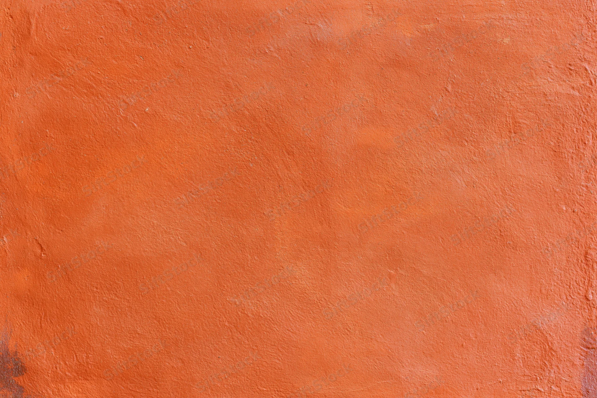 Close-up of an orange stucco plaster wall with textured surface and rough finish